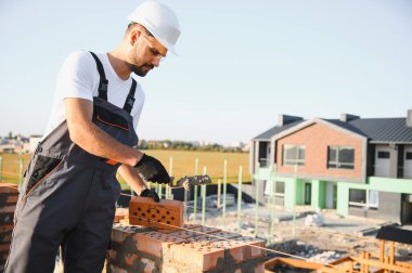 Üniformalı inşaat işçisi ve güvenlik ekipmanı inşaatında çalışıyor.