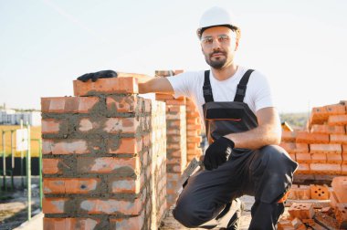 Üniformalı inşaat işçisi ve güvenlik ekipmanı inşaatında çalışıyor.