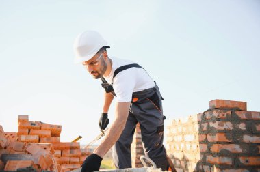 Installing brick wall. Construction worker in uniform and safety equipment have job on building.