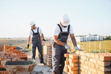 Hintli inşaat işçileri bir tuğla ev inşaatında çalışıyorlar. Bir tuğla duvar inşaatı.