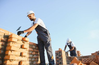 Profesyonel inşaat işçileri bir tuğla ev inşa ediyorlar. Konut inşaatı endüstriyel teması.