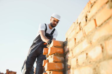 İnşaat alanına tuğla döşeyen bir adam..