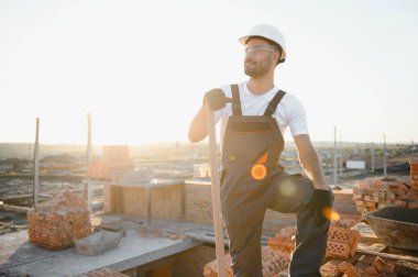 Construction worker in uniform and safety equipment have job on building. Industrial theme.