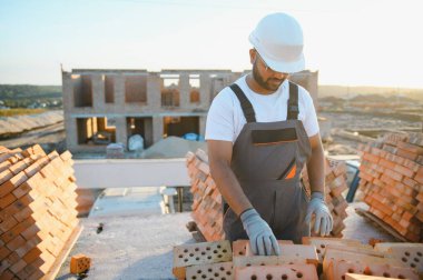 Installing brick wall. Construction worker in uniform and safety equipment have job on building.