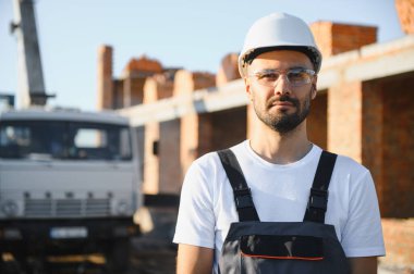 Üniformalı inşaat işçisi ve güvenlik ekipmanı inşaatında çalışıyor.