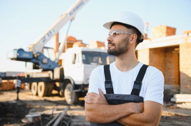 Üniformalı inşaat işçisi ve güvenlik ekipmanı inşaatında çalışıyor.