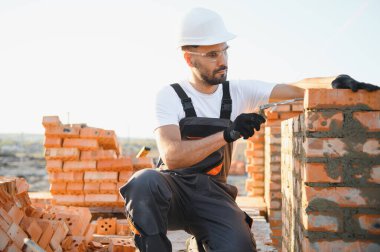 Construction worker in uniform and safety equipment have job on building.