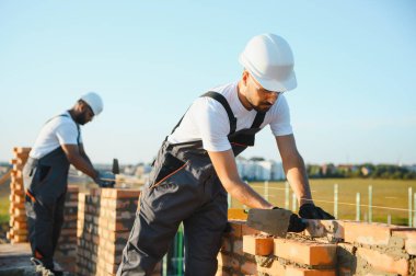 Profesyonel inşaat işçileri bir tuğla ev inşa ediyorlar. Konut inşaatı endüstriyel teması.