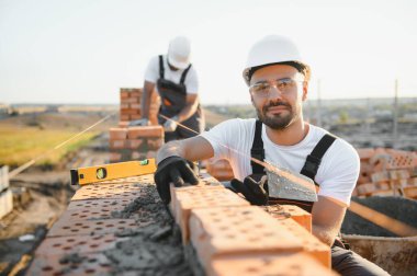 İnşaat alanına tuğla döşeyen bir adam..