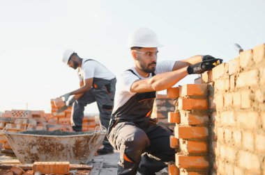 Profesyonel inşaat işçileri bir tuğla ev inşa ediyorlar. Konut inşaatı endüstriyel teması.