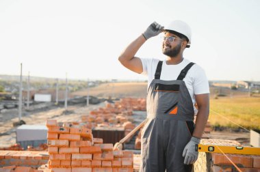 Construction worker man in work clothes and a construction helmet. Portrait of positive male builder in hardhat working at construction site.