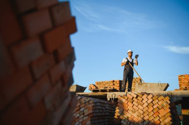 Üniformalı inşaat işçisi ve güvenlik ekipmanı inşaatında çalışıyor.