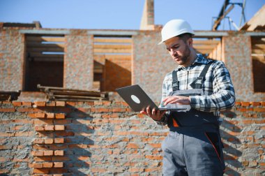 İnşaat alanında dizüstü bilgisayarı izleme sürecine sahip mimar veya mühendis.