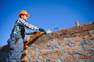 Installing brick wall. Construction worker in uniform and safety equipment have job on building.