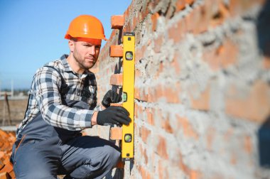 Yeni kırmızı tuğla duvar açık kontrol etmek için bir ruh düzeyi kullanarak Duvarcı ustası. Örmek temelleri duvar örgü teknikleri.