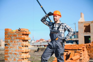 Üniformalı inşaat işçisi ve güvenlik ekipmanı inşaatında çalışıyor.