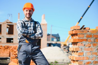 Üniformalı inşaat işçisi ve güvenlik ekipmanı inşaatında çalışıyor.