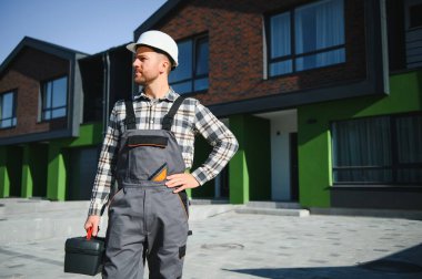 Usta hazır. Tesisatçı ya da inşaatçı bir evin yanında duruyor.