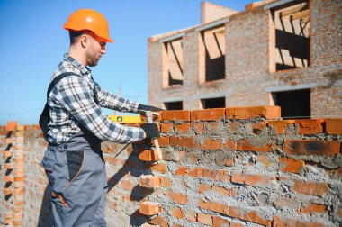 Installing brick wall. Construction worker in uniform and safety equipment have job on building.