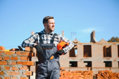 Üniformalı inşaat işçisi ve güvenlik ekipmanı inşaatında çalışıyor.