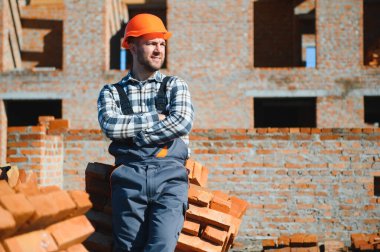 construction mason worker bricklayer installing red brick with trowel putty knife outdoors. clipart