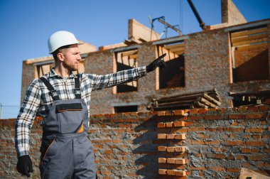 Installing brick wall. Construction worker in uniform and safety equipment have job on building.