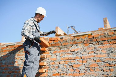 Installing brick wall. Construction worker in uniform and safety equipment have job on building.