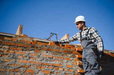 Üniformalı inşaat işçisi ve güvenlik ekipmanı inşaatında çalışıyor.