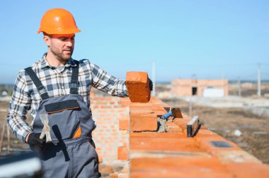 Üniformalı inşaat işçisi ve güvenlik ekipmanı inşaatında çalışıyor.