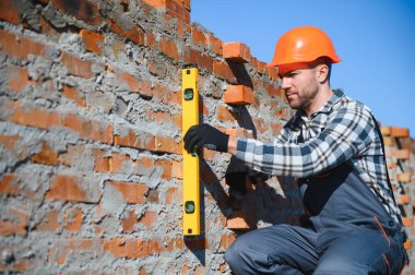 Üniformalı inşaat işçisi ve güvenlik ekipmanı inşaatında çalışıyor.