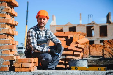 Üniformalı inşaat işçisi ve güvenlik ekipmanı inşaatında çalışıyor.