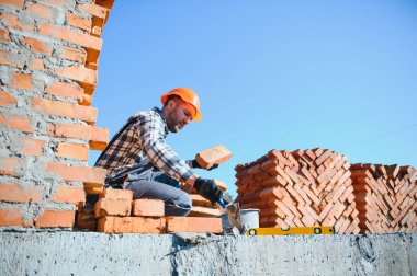 Installing brick wall. Construction worker in uniform and safety equipment have job on building.