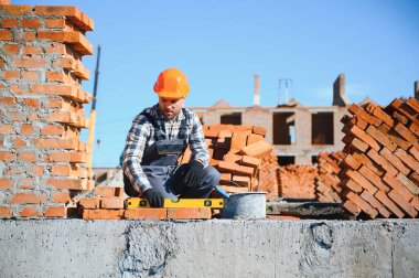 Üniformalı inşaat işçisi ve güvenlik ekipmanı inşaatında çalışıyor.