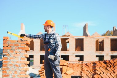 Üniformalı inşaat işçisi ve güvenlik ekipmanı inşaatında çalışıyor.