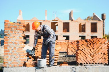 Üniformalı inşaat işçisi ve güvenlik ekipmanı inşaatında çalışıyor.