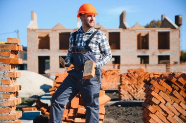 Üniformalı inşaat işçisi ve güvenlik ekipmanı inşaatında çalışıyor.