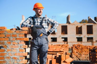 Üniformalı inşaat işçisi ve güvenlik ekipmanı inşaatında çalışıyor.