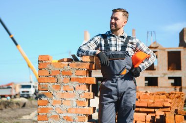 Üniformalı inşaat işçisi ve güvenlik ekipmanı inşaatında çalışıyor.