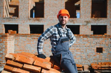 Üniformalı inşaat işçisi ve güvenlik ekipmanı inşaatında çalışıyor.