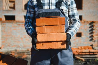 Üniformalı inşaat işçisi ve güvenlik ekipmanı inşaatında çalışıyor.