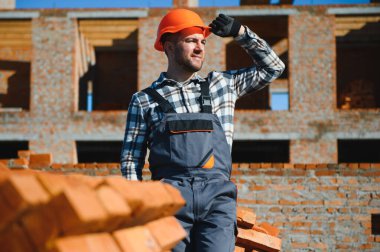 Construction worker in uniform and safety equipment have job on building.