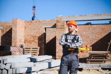 Üniformalı inşaat işçisi ve güvenlik ekipmanı inşaatında çalışıyor.