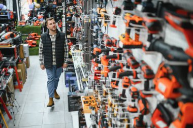 Bir adam hırdavatçıdan elektrikli bir alet seçer. Bir adam hırdavatçıdan elektrikli bir alet seçer..