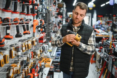 Bir adam hırdavatçıdan elektrikli bir alet seçer..