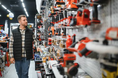 Erkek bir alıcı hırdavatçıdan elektrikli aletler seçer. Büyük bir araç seçimi.