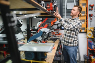 Bir adam hırdavatçıdan elektrikli bir alet seçer..