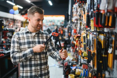 Modern bir hırdavatçıda erkek bir alıcı. Geniş araç gereçler, çeşitli ev eşyaları ve inşaat malzemeleri..