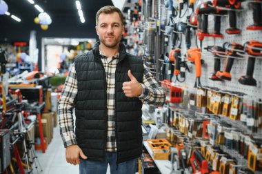 Emin gülümseyen satıcı üzerinde güç araçları deposu ön planda. Adam arka plan istemcilerde yardımcı olmak hazırdır.