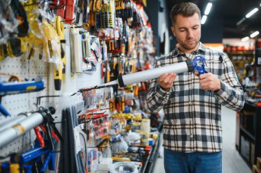 Modern bir hırdavatçıda erkek bir müşteri silikon silah seçiyor..