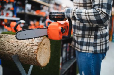 Alet dükkanında elektrikli testereyi tutan adam.